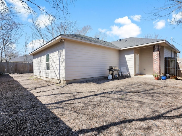 back of house with brick siding and fence