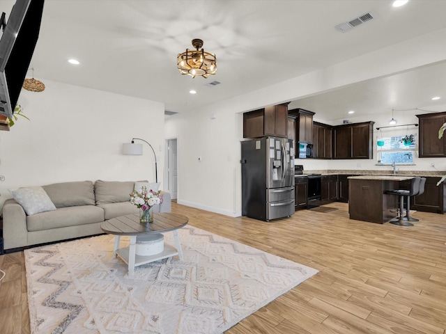 living room with recessed lighting, visible vents, baseboards, and light wood finished floors