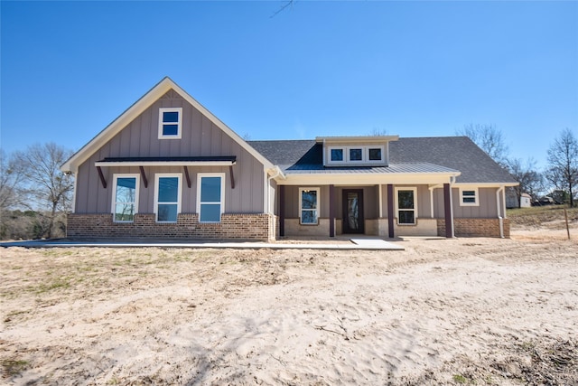 view of front of property with metal roof, brick siding, board and batten siding, and a standing seam roof