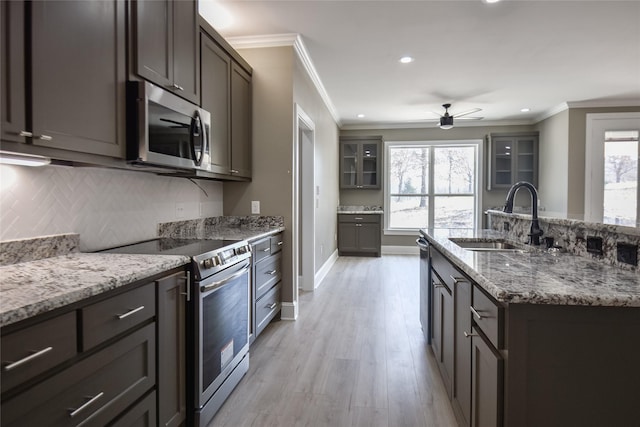 kitchen with a sink, stainless steel appliances, plenty of natural light, and ornamental molding