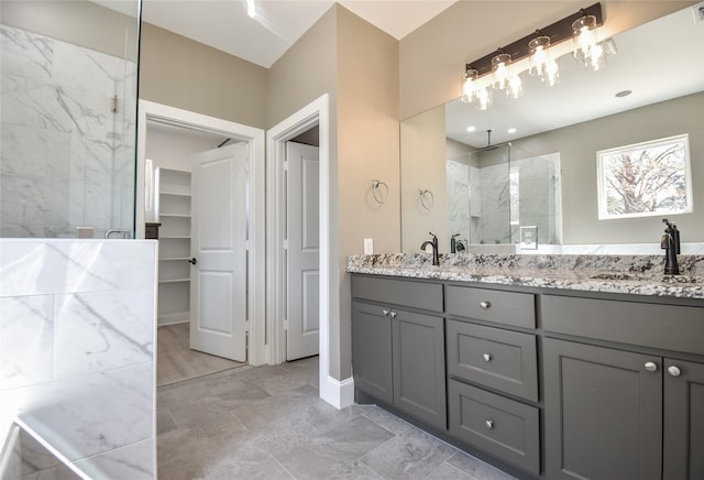 bathroom featuring visible vents, a marble finish shower, double vanity, a sink, and a spacious closet