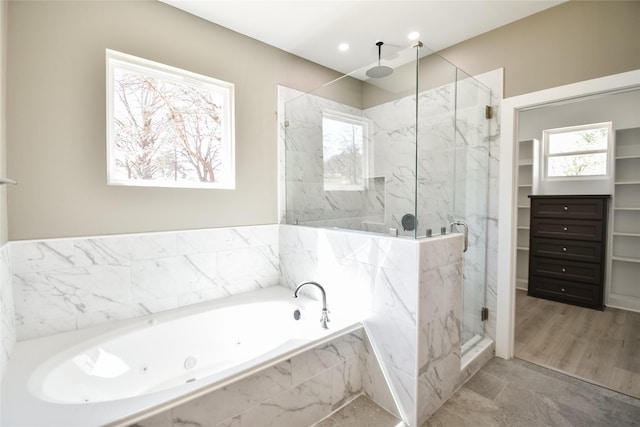 bathroom with a walk in closet, recessed lighting, a tub with jets, and a marble finish shower