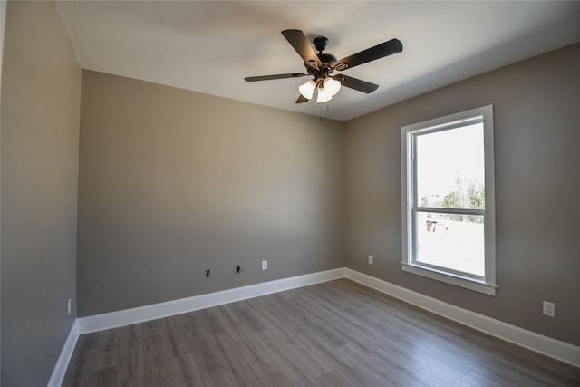 empty room featuring baseboards, wood finished floors, and a ceiling fan