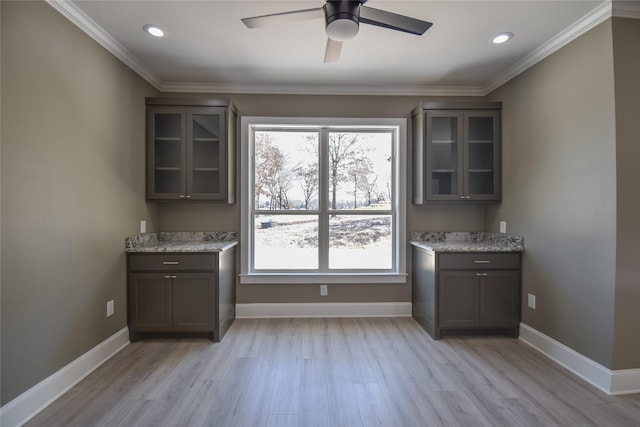 interior space with gray cabinets, glass insert cabinets, baseboards, and ornamental molding