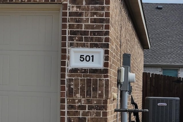 exterior details with fence, central AC, and brick siding