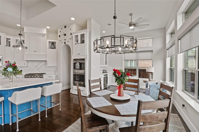 dining area with beverage cooler, arched walkways, dark wood finished floors, baseboards, and recessed lighting