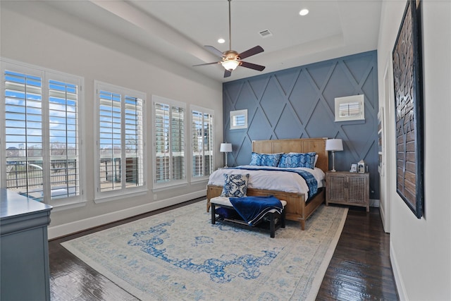 bedroom featuring recessed lighting, wood finished floors, visible vents, baseboards, and a raised ceiling