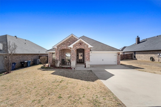 view of front of house featuring a garage, concrete driveway, roof with shingles, a front lawn, and brick siding