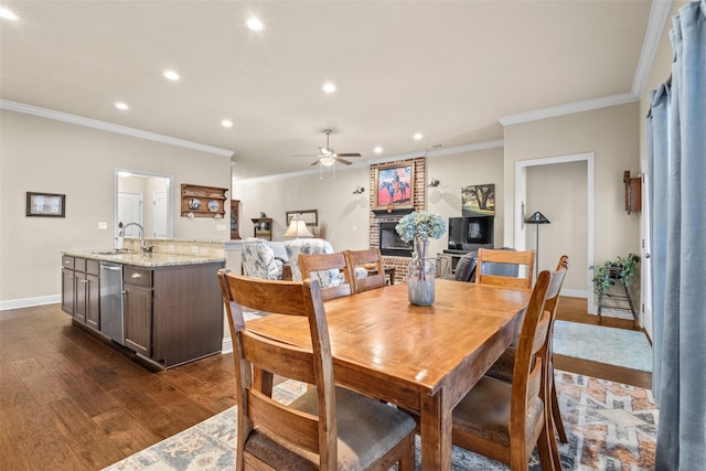 dining space featuring recessed lighting, dark wood-style flooring, a brick fireplace, and crown molding