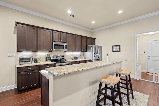 kitchen with appliances with stainless steel finishes, visible vents, dark brown cabinetry, and dark wood-style floors