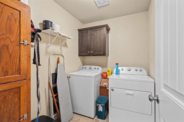 laundry area featuring visible vents, washing machine and clothes dryer, and cabinet space