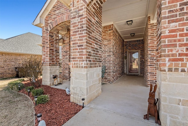 view of exterior entry featuring driveway and brick siding