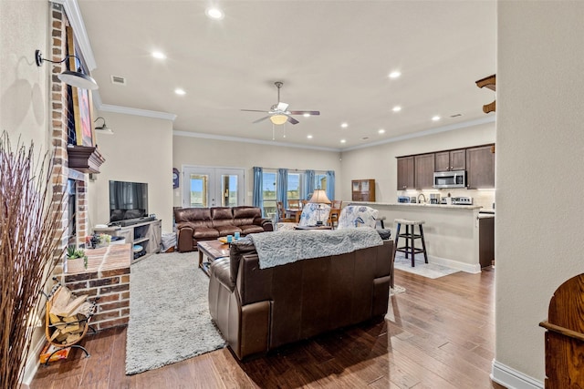 living area with crown molding, recessed lighting, visible vents, a ceiling fan, and hardwood / wood-style flooring