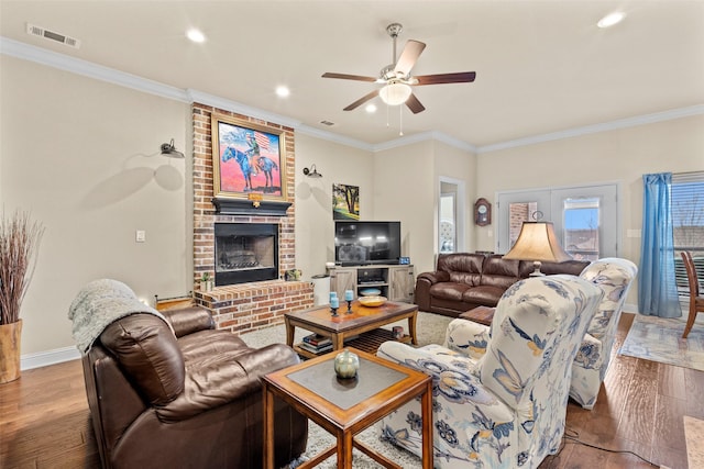 living room featuring a fireplace, wood finished floors, visible vents, and crown molding