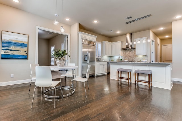 6005 Monte Cristo Ln, Plano, TX 75024 - kitchen featuring wall chimney exhaust hood, appliances with stainless steel finishes, white cabinetry, dark wood-style floors, and baseboards