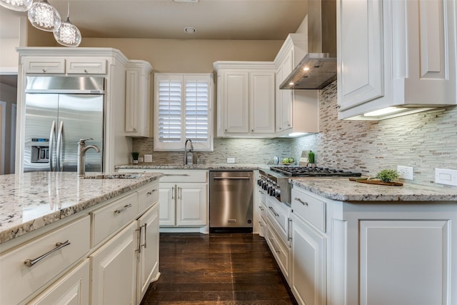 6005 Monte Cristo Ln, Plano, TX 75024 - kitchen featuring stainless steel appliances, wall chimney range hood, a sink, dark wood-type flooring, and white cabinets