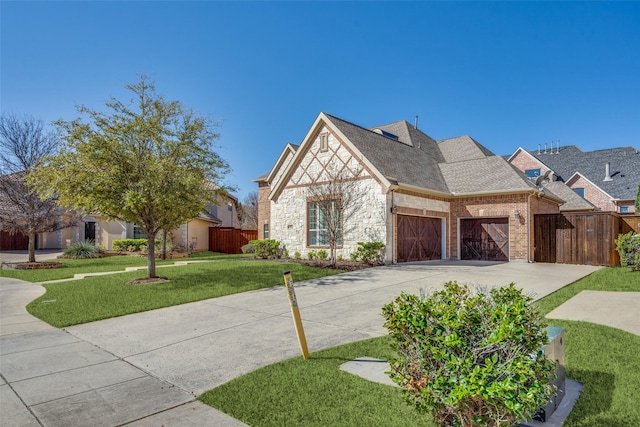 view of front of property with fence, driveway, an attached garage, a front lawn, and brick siding