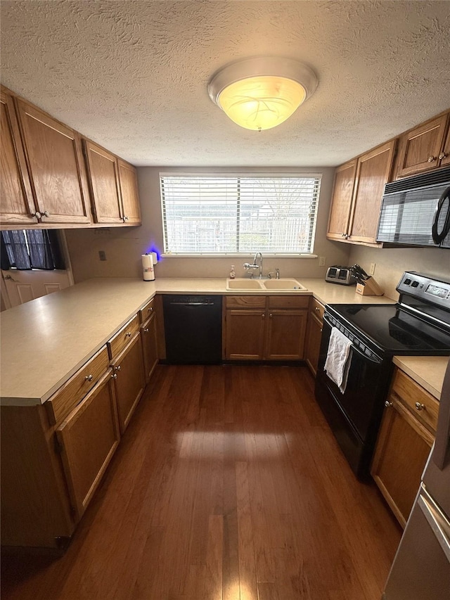 kitchen with black appliances, plenty of natural light, a sink, and dark wood finished floors