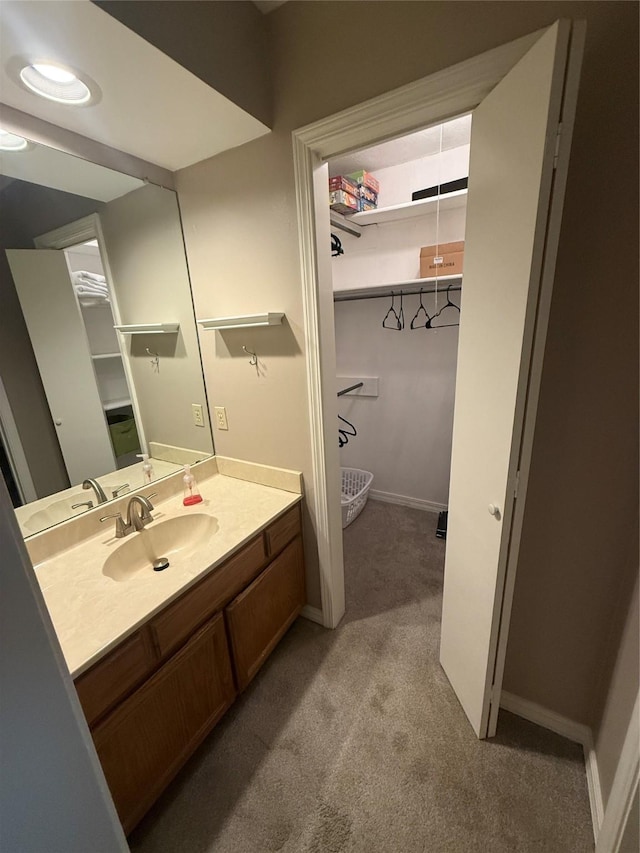 bathroom with baseboards, carpet flooring, and vanity