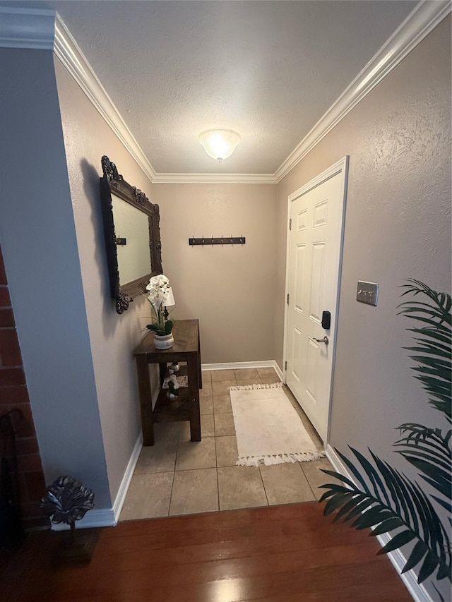 doorway with crown molding, a textured ceiling, baseboards, and light tile patterned floors