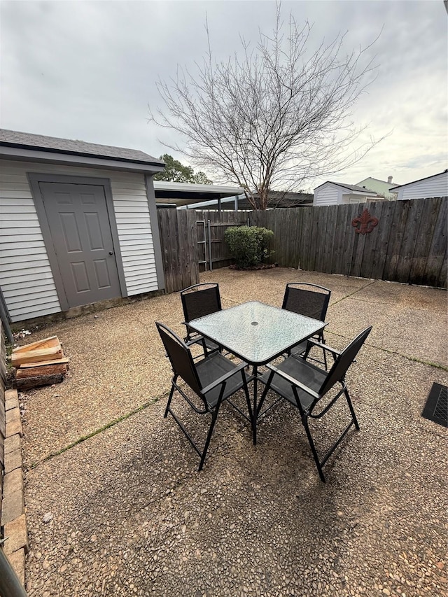 view of patio / terrace featuring outdoor dining area, a fenced backyard, an outdoor structure, and a storage unit