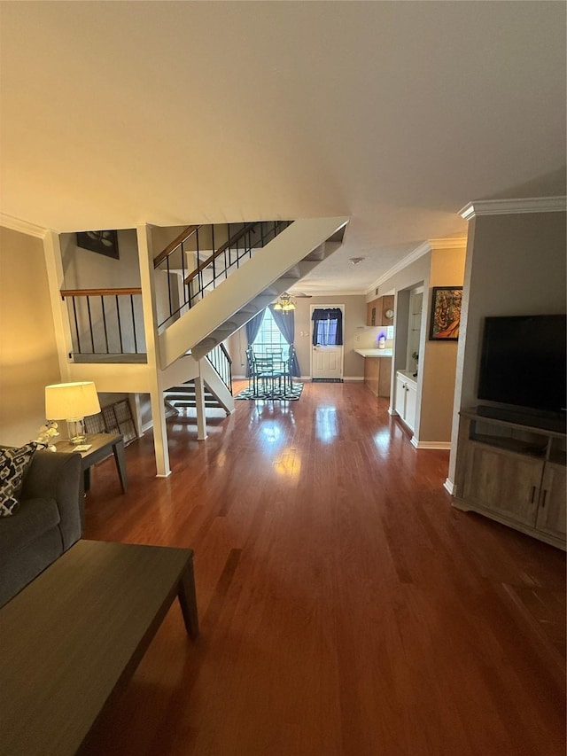 living room featuring baseboards, stairs, ornamental molding, and wood finished floors