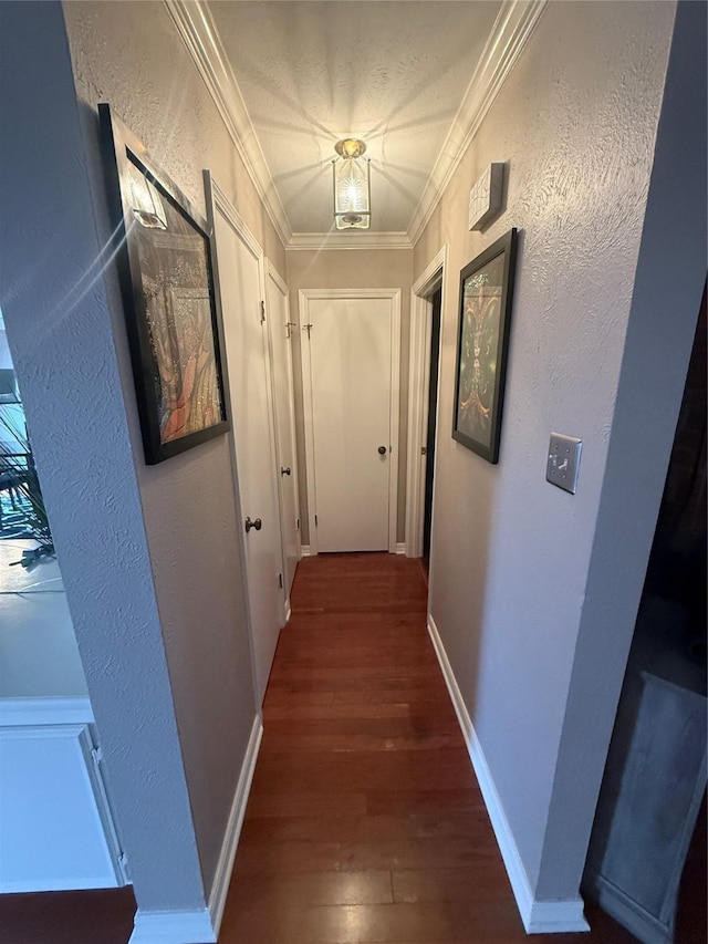 hall featuring baseboards, ornamental molding, wood finished floors, and a textured wall