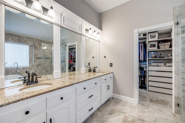 bathroom featuring a walk in closet, a sink, a tile shower, and double vanity