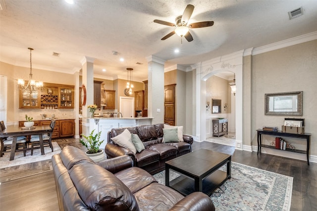 living area featuring dark wood-style floors, arched walkways, visible vents, and ceiling fan with notable chandelier