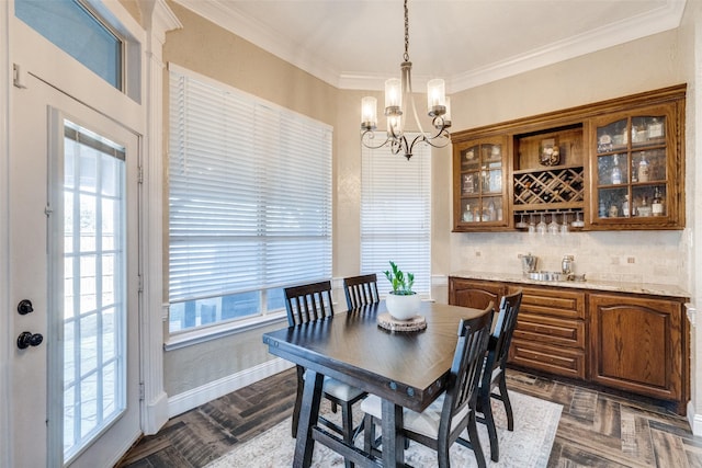 dining room with baseboards, ornamental molding, indoor bar, and a notable chandelier