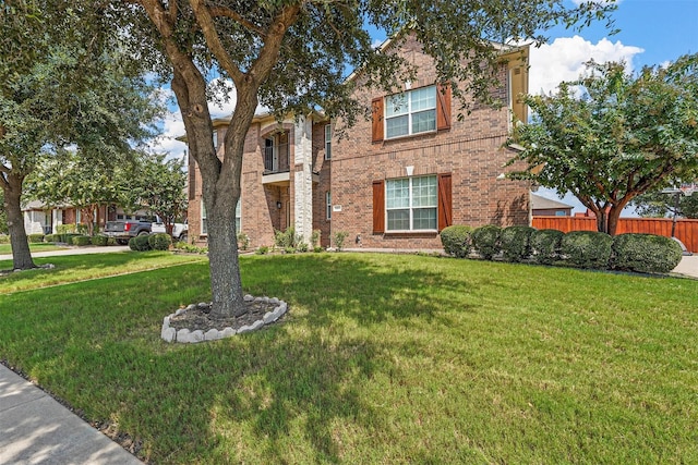 traditional-style house featuring a front yard, brick siding, and fence