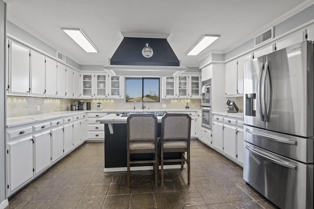 kitchen with stainless steel appliances, white cabinetry, island exhaust hood, and backsplash