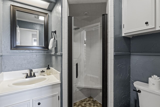 bathroom featuring a textured wall, vanity, a shower stall, and toilet