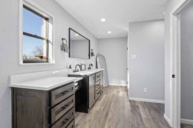 interior space featuring light countertops, light wood-style floors, a sink, dark brown cabinets, and baseboards