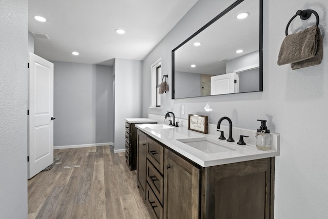 bathroom with double vanity, a sink, baseboards, and wood finished floors