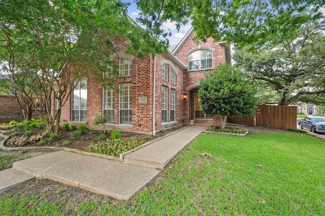 view of front of house with a front yard, brick siding, and fence