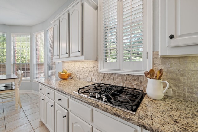 kitchen with light stone counters, light tile patterned floors, black gas cooktop, tasteful backsplash, and white cabinets