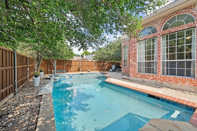 view of pool featuring a fenced backyard and a pool with connected hot tub