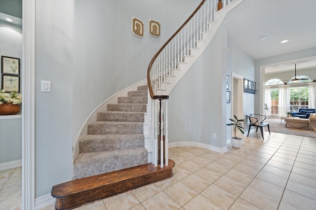 staircase featuring a high ceiling, recessed lighting, tile patterned flooring, and baseboards