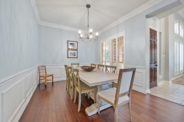 dining space featuring a chandelier, ornamental molding, a decorative wall, and wood finished floors