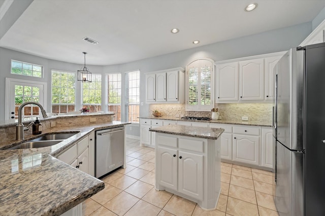 kitchen featuring tasteful backsplash, visible vents, a kitchen island, appliances with stainless steel finishes, and a sink