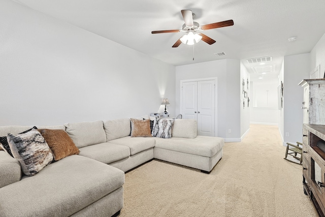 living area featuring baseboards, visible vents, ceiling fan, and light colored carpet