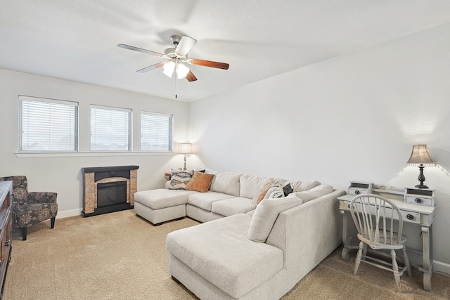 living room with a textured ceiling, carpet floors, a fireplace, a ceiling fan, and baseboards