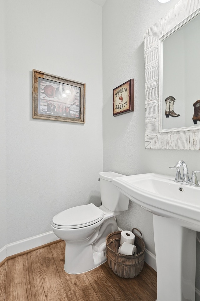 bathroom featuring baseboards, toilet, and wood finished floors