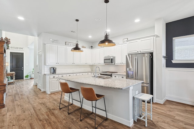 kitchen with stainless steel appliances, white cabinetry, light wood-style floors, and a kitchen breakfast bar