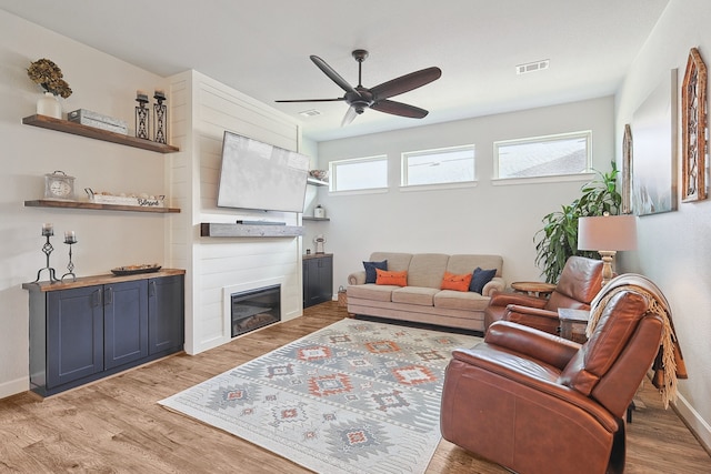 living area with light wood-type flooring, visible vents, a fireplace, and baseboards