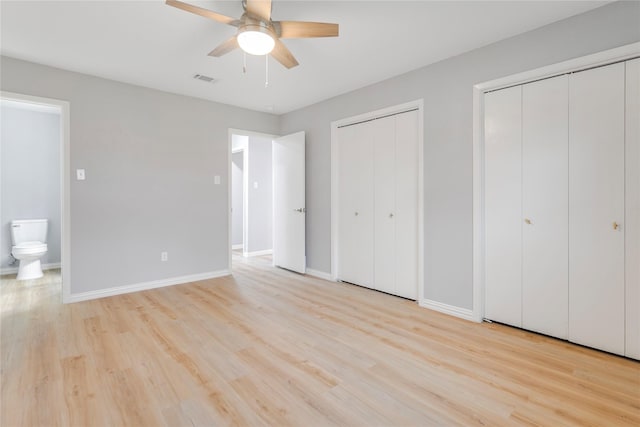 unfurnished bedroom featuring light wood finished floors, visible vents, baseboards, a ceiling fan, and multiple closets