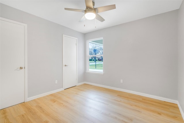 spare room featuring light wood-style flooring, baseboards, and a ceiling fan