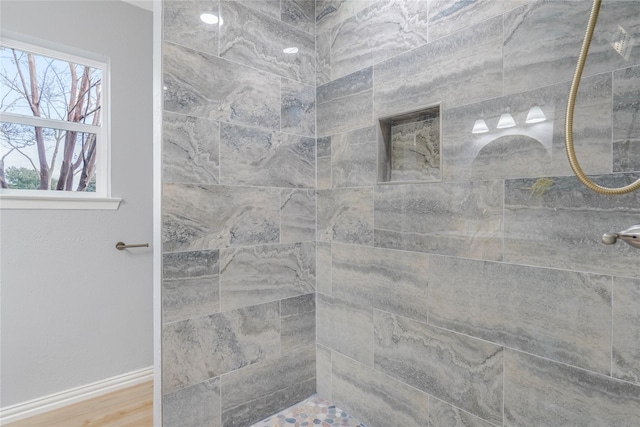 bathroom featuring tiled shower, baseboards, and wood finished floors