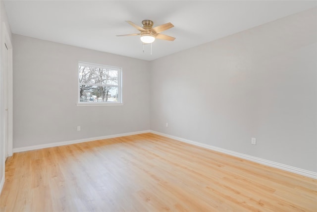 spare room with light wood finished floors, baseboards, and a ceiling fan